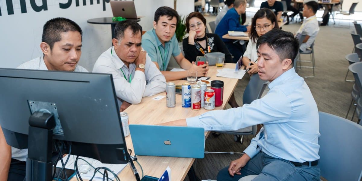 A team reviewing a laptop screen together at GenAI Open Innovation Vietnam